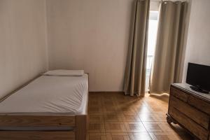 Un pequeño dormitorio con una cama y un televisor. en Olvera B&B Hostel en Olvera, en Olvera