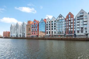 a row of buildings next to a body of water at Dom & House - Apartments Granaria in Gdańsk