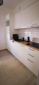 a kitchen with white cabinets and a wooden floor at Apartments Katarina in Stara Novalja