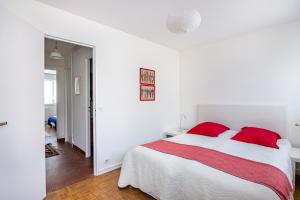 a white bedroom with a large bed with red pillows at Le Saint É in Dinard