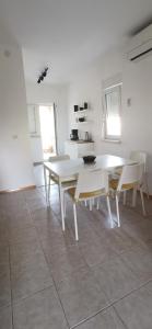 ein weißes Esszimmer mit einem weißen Tisch und Stühlen in der Unterkunft Apartments Katarina in Stara Novalja