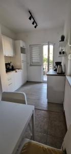 a kitchen with white cabinets and a table in a room at Apartments Katarina in Stara Novalja