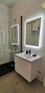 a white bathroom with a sink and a mirror at Apartments Katarina in Stara Novalja