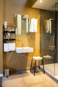 y baño con lavamanos, ducha y taburete. en Hotel1875, en Amberes