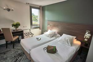バイヨンヌにあるコンフォート ホテル ロレアクのベッド2台とデスクが備わるホテルルームです。