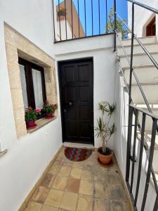 a black door on a white building with potted plants at Residenza Eos in Siracusa