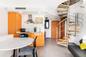 una escalera de caracol en una cocina con mesa y sillas en Aparthotel Las Palmeras Castelldefels, en Castelldefels