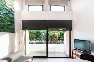 a living room with a large window and a tv at Aparthotel Las Palmeras Castelldefels in Castelldefels