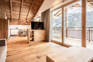 a living room with a tv and large windows at Luxury Chalet Plazola in Selva di Val Gardena