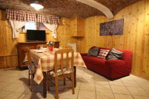 - un salon avec une table et un canapé rouge dans l'établissement L'ermellino Bilocale in Centro - Affitti Brevi Italia, à Brusson