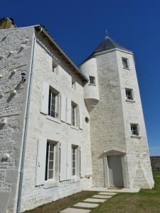 un grand bâtiment en briques blanches avec une tour dans l'établissement Logis de Pierre Levée, à Bessines