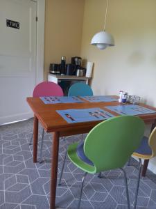 una mesa con sillas coloridas alrededor en una habitación en Bed & Kitchen „Den gamle Skole“ Nr. Sejerslev, en Højer
