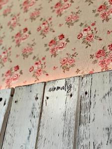a table with a cloth with red flowers on it at Stefans Gästezimmer in Kirchhatten
