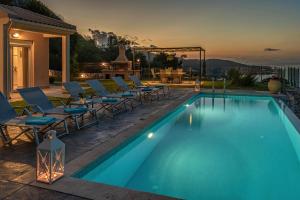 a swimming pool with chairs and a table on a patio at Ionian Heaven Villas in Nikiana