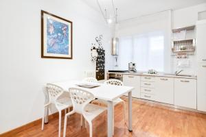 een witte keuken met een witte tafel en stoelen bij Ospedale & Galleria Ognissanti Apartment in Padua