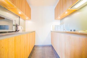 cocina con armarios de madera y microondas en Les studios du Verger, en Durbuy