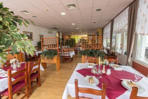 a restaurant with white tables and chairs and plants at Hotel Klek in Ogulin