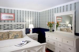 een slaapkamer met een wit bed en een spiegel bij Queen Anne Inn in Chatham