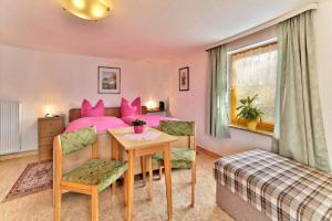 una camera da letto con tavolo e letto con cuscini rosa di Pension Maria a Hauzenberg