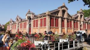 pessoas andando em frente a um grande edifício com flores em Colmar Nature - Quiet Apartment MARAICHERS em Colmar