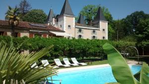 a resort with a pool in front of a castle at Hotel Logis - Chateau de Beauregard in Saint-Girons