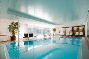 een groot zwembad met blauw water in een gebouw bij Hotel Hohes Licht in Damuls