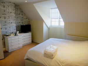 a bedroom with a white bed and a television at The Saracens Head Hotel in Highworth