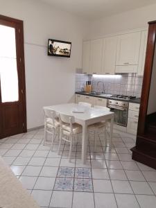 a white kitchen with a white table and chairs at Casa Marcella San Vito Lo Capo in San Vito lo Capo