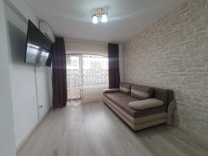 a living room with a couch and a brick wall at Apartament Posada in Curtea de Argeş
