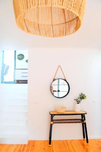 a rattan mirror hanging above a table in a room at Verde'Água Family Home in Mosteiros