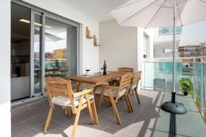 una mesa de madera con sillas y una sombrilla en el balcón en Seafront Duna Beach Luxury Apartment, en Torrox