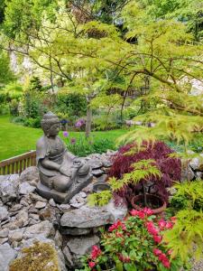 a statue of a buddha sitting in a garden at Cascades Gardens in Matlock