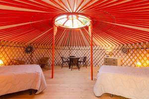 Tienda roja con 2 camas y mesa. en Camping El Roble en Valderrobres