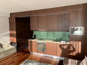 a kitchen with wooden cabinets and a sink and a couch at Bavaria Club Apartman in Balatonlelle