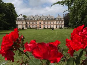 una casa grande con rosas rojas delante de ella en Château de Sissi en Sassetot-le-Mauconduit
