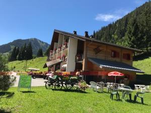 un bâtiment avec des tables et des chaises devant lui dans l'établissement Au Bois de Lune, à Châtel