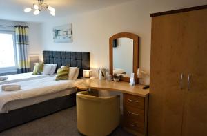a bedroom with a bed and a desk with a mirror at The Angel Hotel in Cardigan