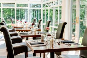 um restaurante com mesas e cadeiras de madeira e janelas em Craig-y-Dderwen Riverside Hotel em Betws-y-coed