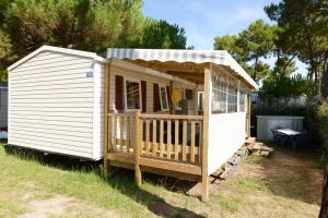 a small white shed with a porch on the grass at Camping la Palmyre in Les Mathes