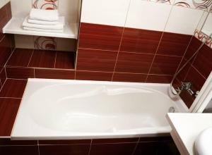 a white bath tub in a bathroom with brown tiles at Apartmán 224 in Mikulov
