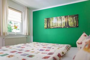 a bedroom with a green wall with a bed and a window at Ferienhaus Giesela **** in Wernigerode