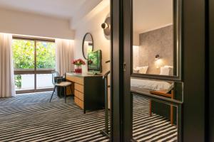 um quarto com uma cama, uma secretária e um espelho em D. Afonso Hotel & SPA em Monte Real