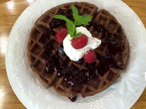 a white plate with a waffle with berries and syrup at The Bed and Breakfast at Oliver Phelps in Canandaigua