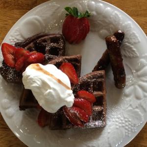 a plate of waffles with strawberries and whipped cream at The Bed and Breakfast at Oliver Phelps in Canandaigua