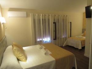 Habitación de hotel con 2 camas con sábanas blancas en Albergue El Encuentro, en Villanueva de la Vera