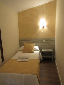 um quarto com duas camas e uma luz na parede em Albergue El Encuentro em Villanueva de la Vera