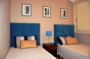 um quarto com duas camas com cabeceiras azuis e quadros na parede em Ponta Grande Sao Rafael Resort by Umbral em Albufeira