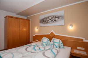 Schlafzimmer mit einem Bett mit blauen und weißen Kissen in der Unterkunft Apart Bel Ami in Kappl