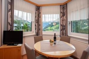 a dining room with a table and a tv and two windows at Apart Bel Ami in Kappl