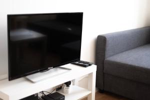 a flat screen tv on a white table next to a couch at Comfort Apartments - Stephansdom in Vienna